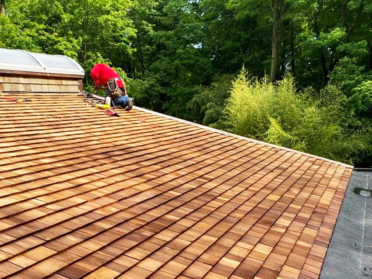 Nu-Fix crew member installing cedar shake shingles near a skylight