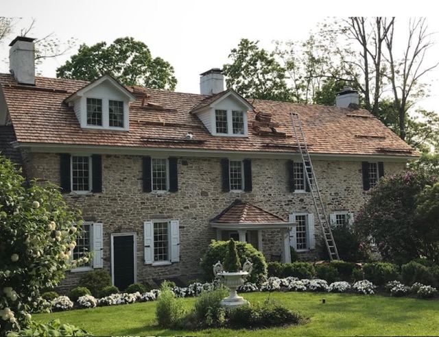 Large stone colonial home with a new cedar shake roof