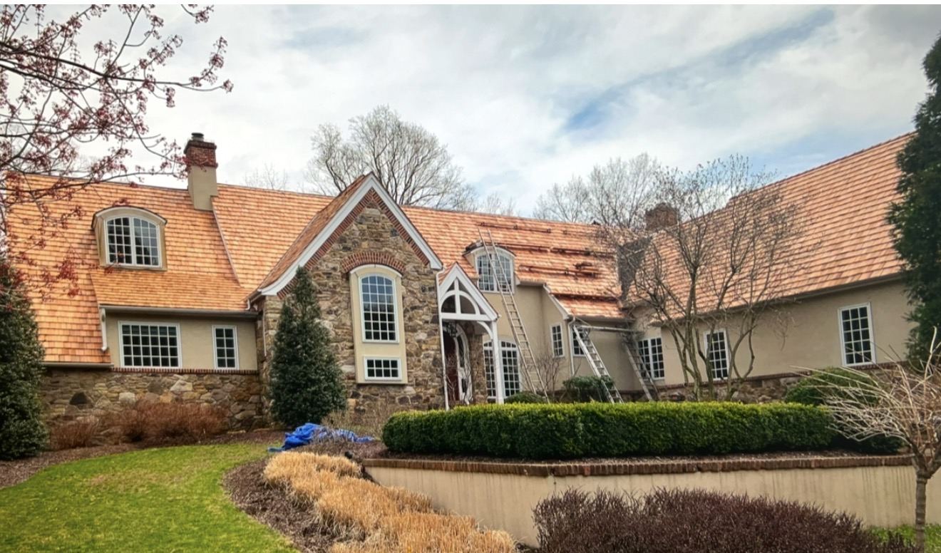 New cedar shake roof with copper flashing on a stone Tudor-style home