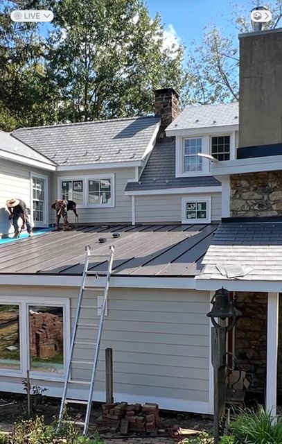 Crew installing a standing seam metal roof over an existing roof, aerial view