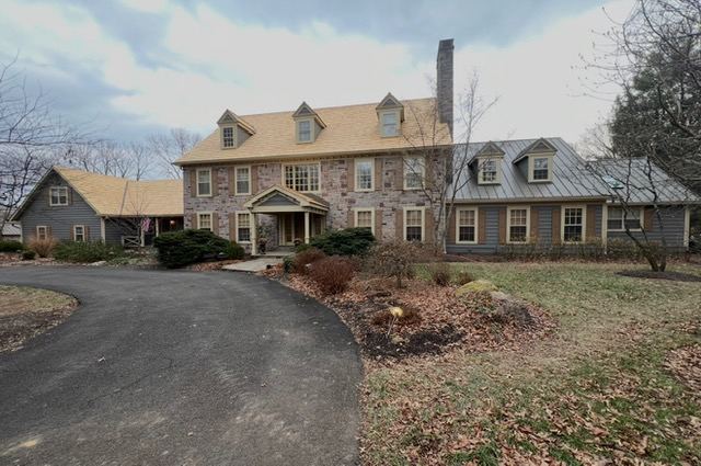 Stone colonial home with new shingle roof and standing seam metal addition