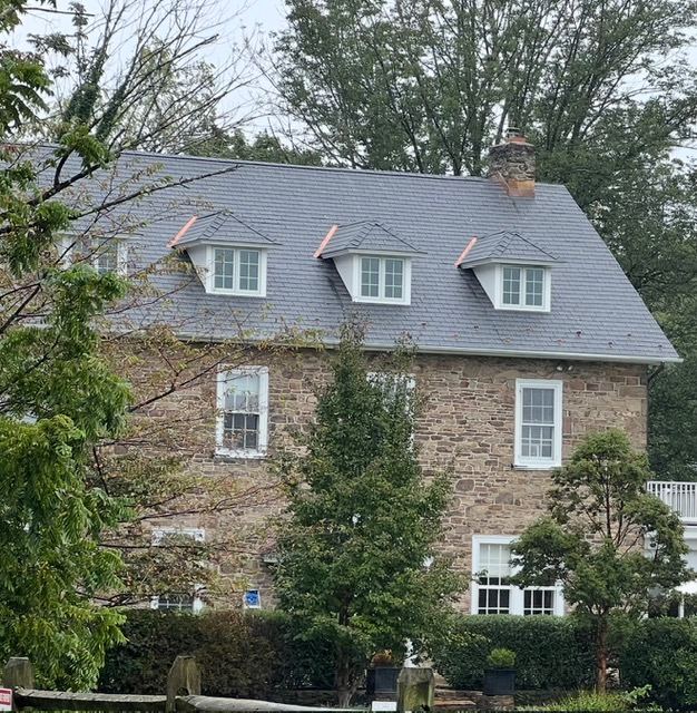 Stone farmhouse with new architectural shingle roof and copper-capped dormers